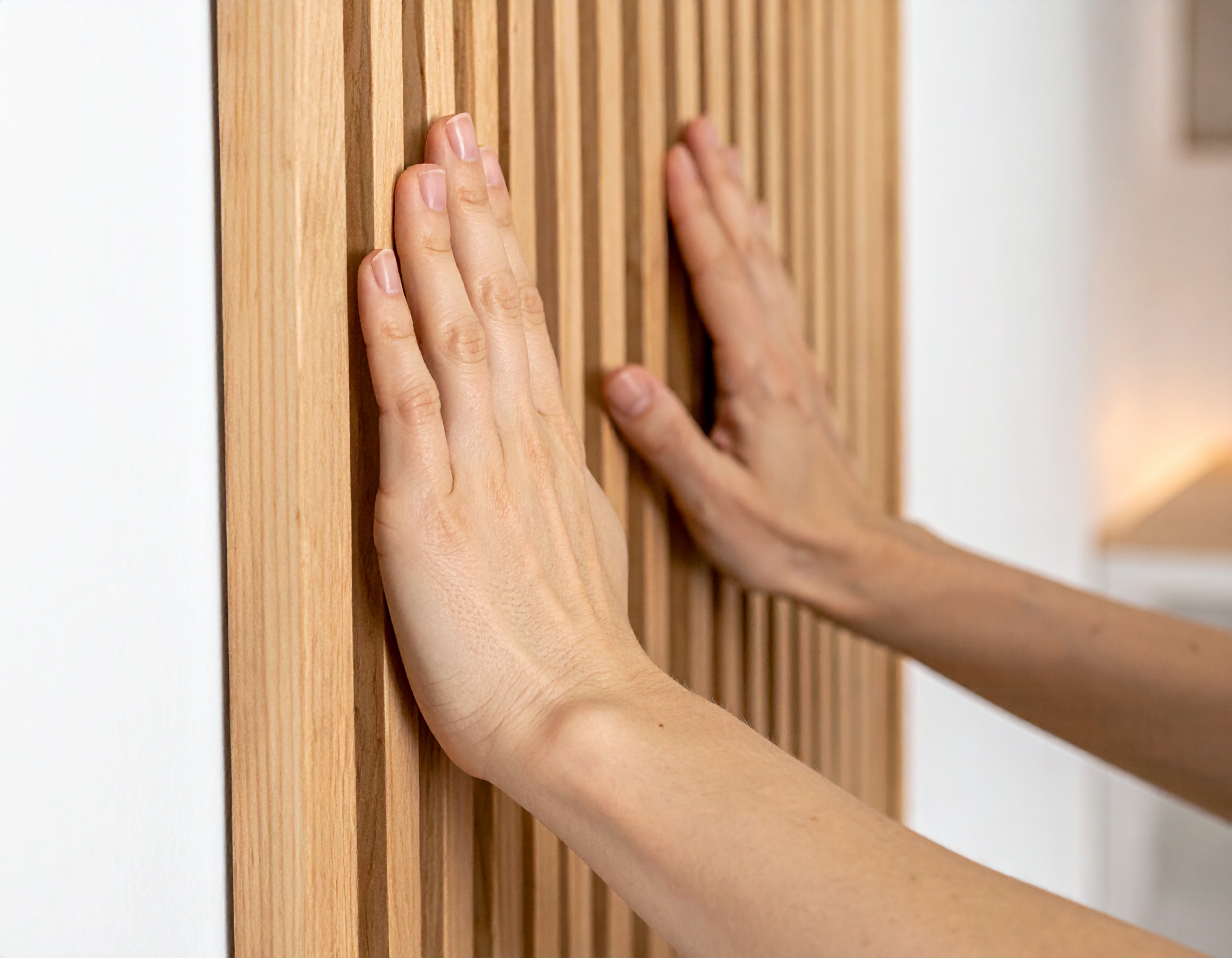 Akustikpaneele selbst montieren – Schritt für Schritt Montage von AKUSTIL Holz-Akustikpaneelen in Eiche – Hände drücken Wandpaneel an Wohnraumwand